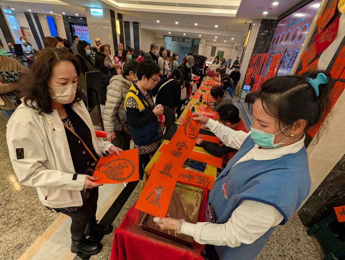 ▲醫院志工幫民眾春聯撒上金粉添喜氣。