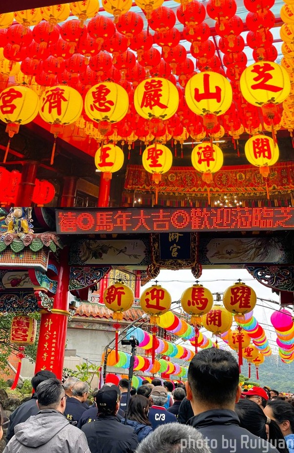 上午約9時50分，通往芝山巖惠濟宮的入口及階梯湧入走春人潮；廟內高掛紅黃燈籠，「芝山巖惠濟宮」及「開漳聖王」字樣排列醒目，年節氛圍濃厚。（記者陳欣攝）
