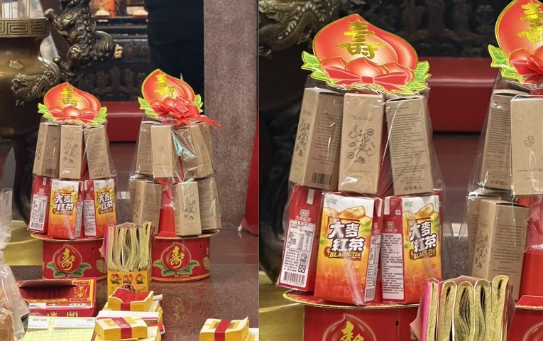 ▲近日有網友分享，在百貨商圈附近的土地公廟中，發現百貨櫃位人員於供桌上擺放大麥紅茶，並以卡其色紙盒堆疊成壽桃塔形狀作為供品，相關畫面引發討論。（網友提供）