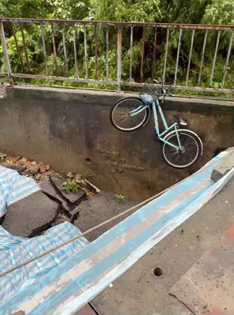 ▲受豪雨影響,楠梓區安泰街182巷發生嚴重路面塌陷、地下土體流失,現場可見路面大面積崩落,連停放的自行車也隨塌陷懸掛在擋土牆邊。